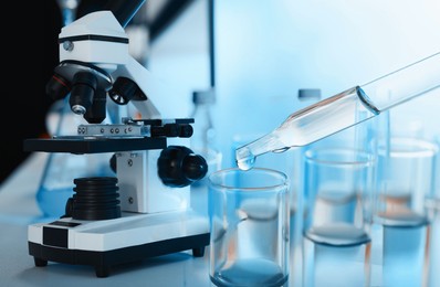 Image of Laboratory analysis. Dripping reagent into test tube, double exposure with microscope