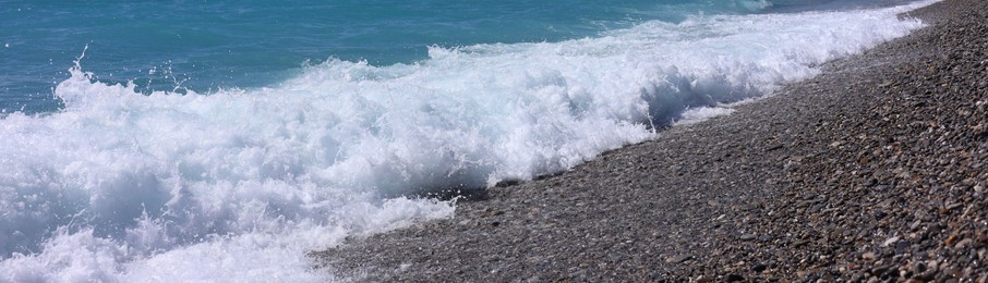 Photo of Beautiful view of wavy sea, city and pebbles on beach