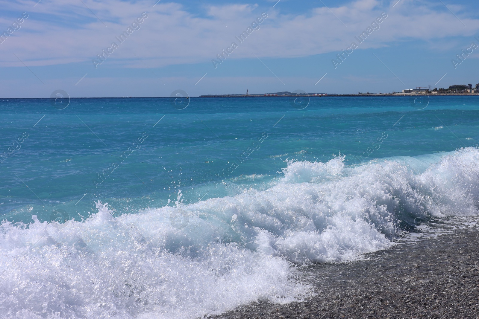 Photo of Beautiful view of wavy sea, city and pebbles on beach