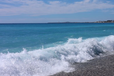 Photo of Beautiful view of wavy sea, city and pebbles on beach