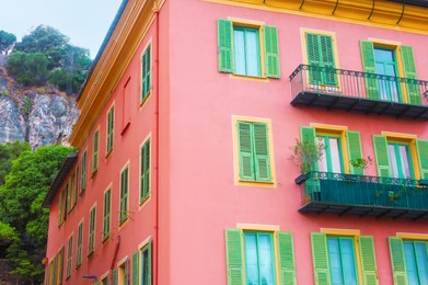 Photo of Beautiful building with windows and balconies against blue sky in city, low angle view