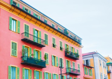 Photo of Beautiful buildings with windows and balconies against blue sky in city, low angle view