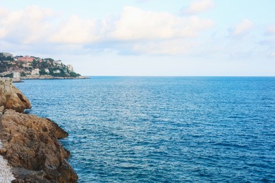 Photo of Picturesque view of sea, city and cliff under blue sky