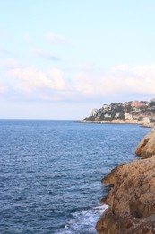 Photo of Picturesque view of sea, city and cliff under blue sky