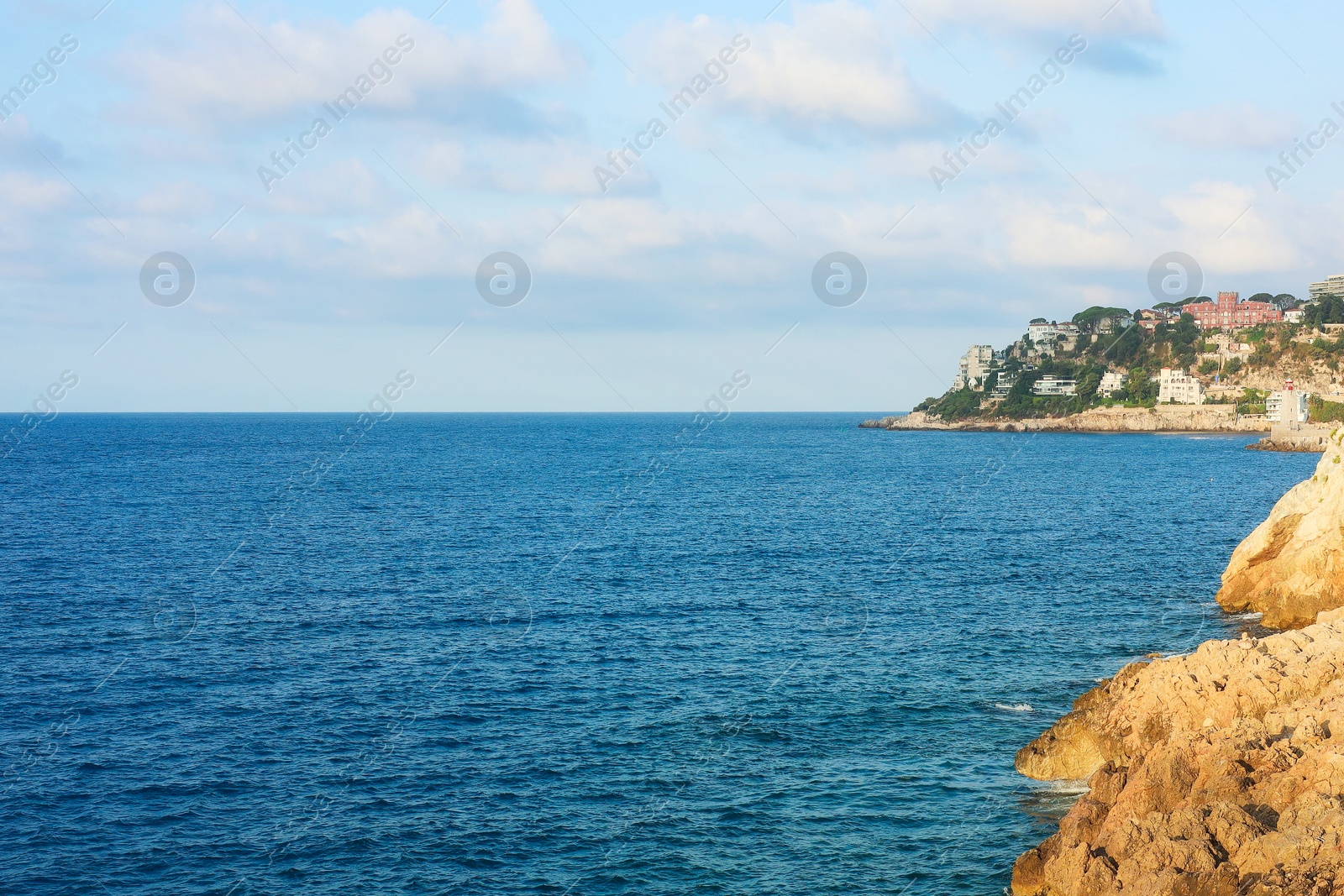 Photo of Picturesque view of sea, city and cliff under blue sky
