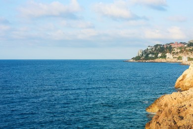 Photo of Picturesque view of sea, city and cliff under blue sky