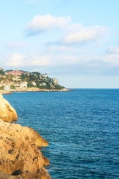 Photo of Picturesque view of sea, city and cliff under blue sky