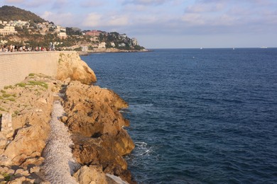 Photo of Picturesque view of sea, city and cliff under blue sky