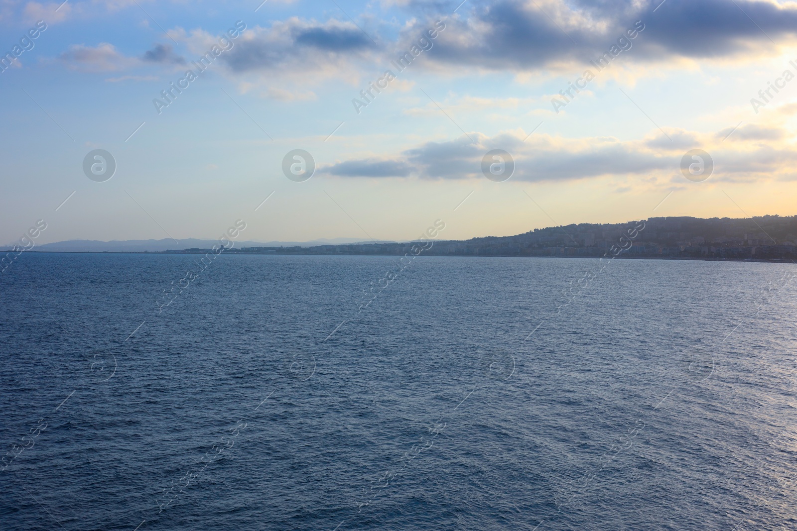 Photo of Beautiful view of wavy sea and mountains under blue cloudy sky