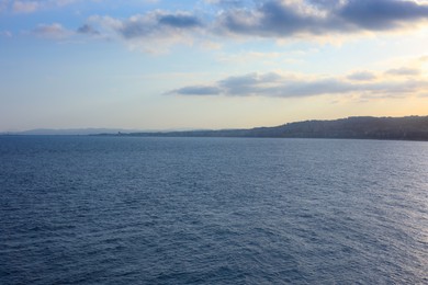 Photo of Beautiful view of wavy sea and mountains under blue cloudy sky