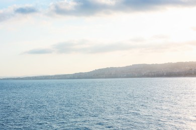 Photo of Beautiful view of wavy sea and mountains under blue cloudy sky