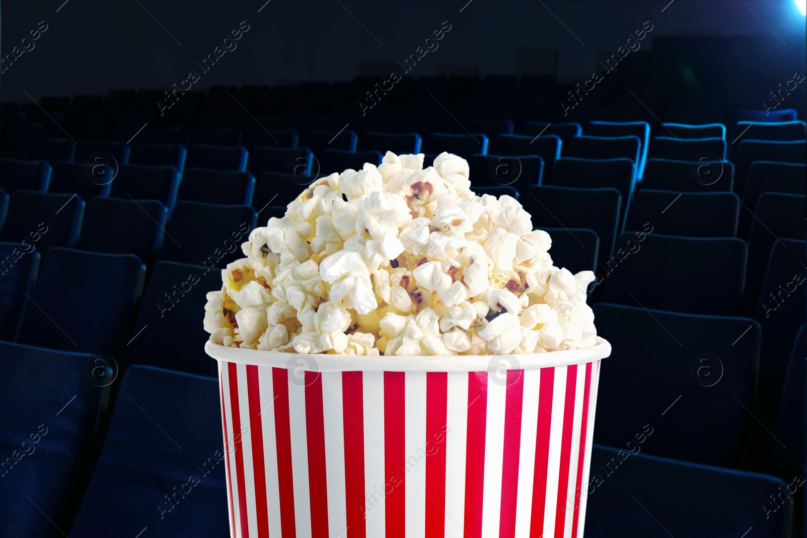 Image of Bucket of fresh popcorn and seats in dark cinema