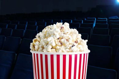 Image of Bucket of fresh popcorn and seats in dark cinema