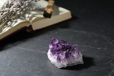 Photo of Beautiful amethyst gemstone, lavender flowers, palo santo and book on black table, closeup