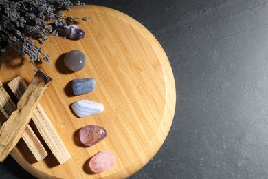 Photo of Different beautiful gemstones, lavender flowers and palo santo on black table, top view. Space for text