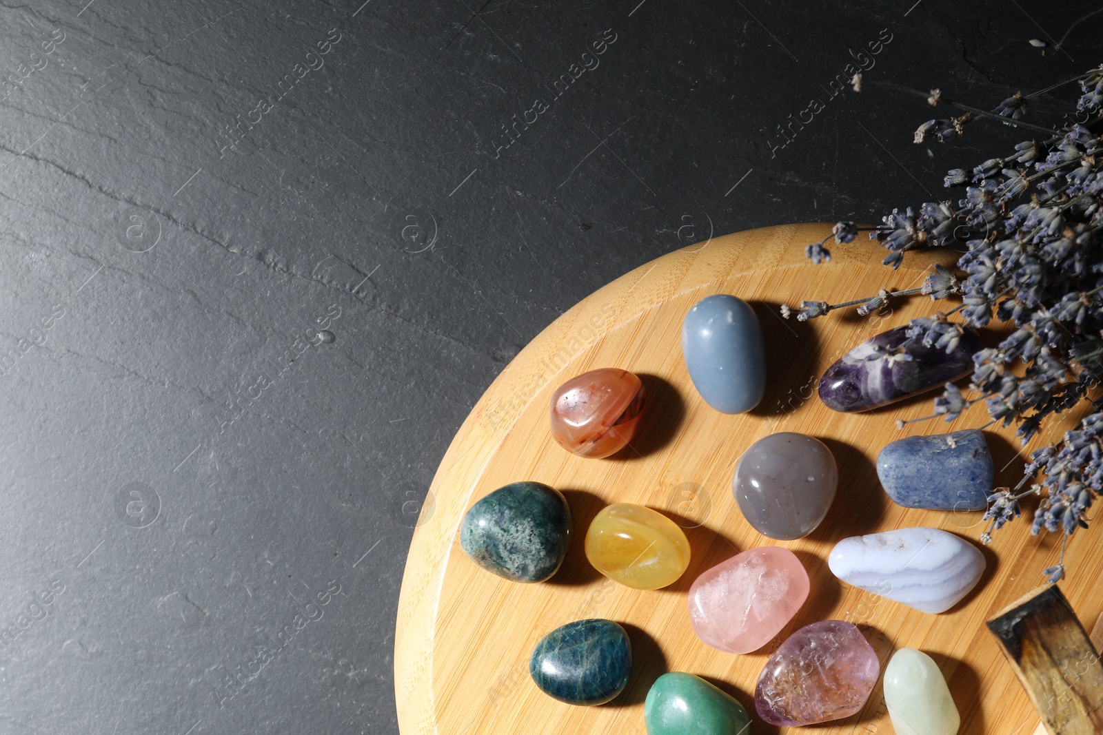 Photo of Different beautiful gemstones, lavender flowers and palo santo on black table, top view. Space for text
