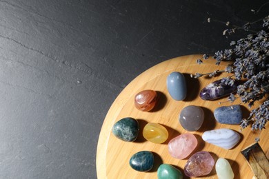 Photo of Different beautiful gemstones, lavender flowers and palo santo on black table, top view. Space for text