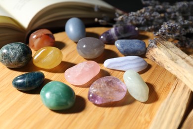 Photo of Different beautiful gemstones, lavender flowers, palo santo and book on table, closeup