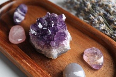 Photo of Different beautiful gemstones and lavender flowers on table, closeup