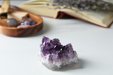 Photo of Different beautiful gemstones, book and lavender flowers on white table, closeup