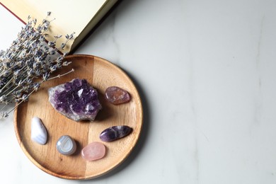 Photo of Different beautiful gemstones, book and lavender flowers on white marble table, flat lay. Space for text