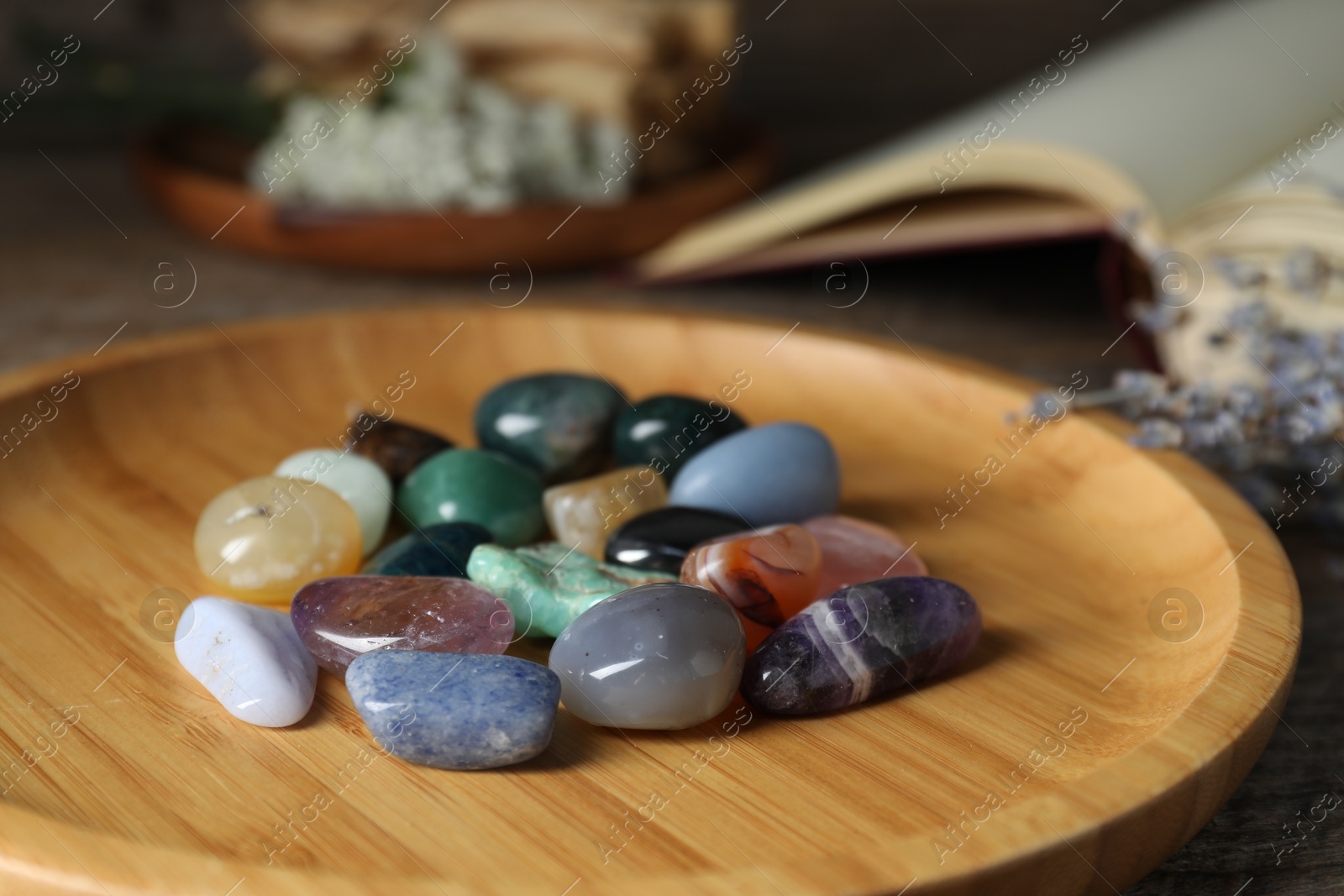 Photo of Different beautiful gemstones, lavender flowers and book on table, closeup