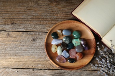 Photo of Different beautiful gemstones, lavender flowers and book on wooden table, flat lay. Space for text