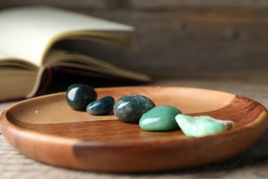 Photo of Different beautiful gemstones and book on table, closeup