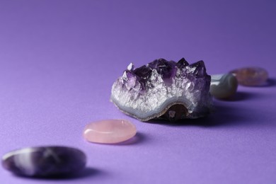 Photo of Different beautiful gemstones on purple background, closeup
