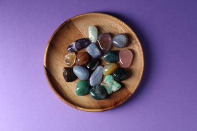 Photo of Different beautiful gemstones on purple background, top view