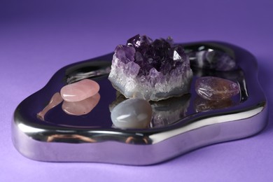 Photo of Different beautiful gemstones on purple background, closeup