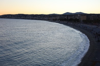 Photo of Picturesque seascape with coastline, people and mountains at sunset