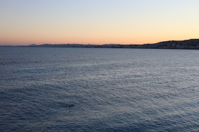 Photo of Beautiful seascape with city and mountains at sunset
