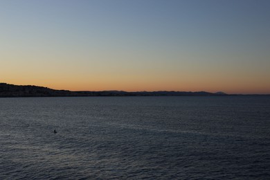 Photo of Beautiful seascape with city and mountains at sunset