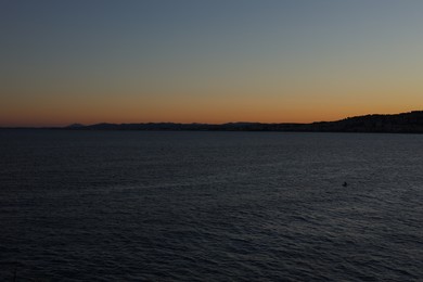 Photo of Beautiful seascape with city and mountains at sunset