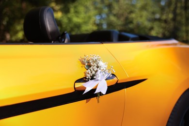 Photo of Wedding car. Cabriolet decorated with beautiful flowers outdoors, closeup