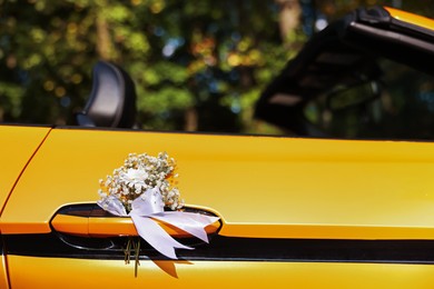 Photo of Wedding car. Cabriolet decorated with beautiful flowers outdoors, closeup