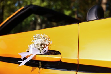Photo of Wedding car. Cabriolet decorated with beautiful flowers outdoors, closeup