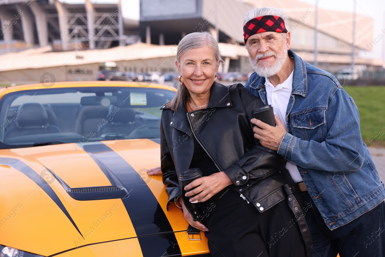 Photo of Stylish senior couple with takeaway coffee near modern cabriolet outdoors