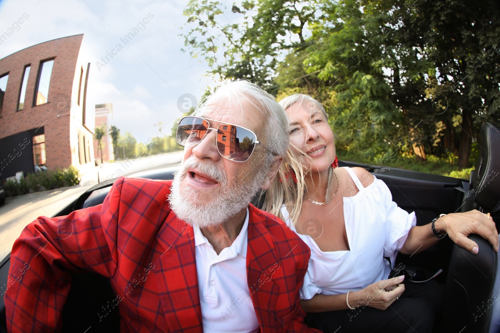 Photo of Senior couple enjoying cabriolet ride in city, wide angle lens