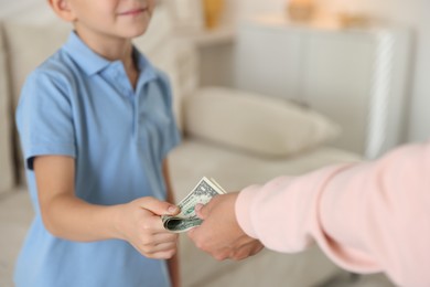 Photo of Mother giving pocket money to her son at home, closeup