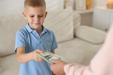 Photo of Mother giving pocket money to her son at home, closeup