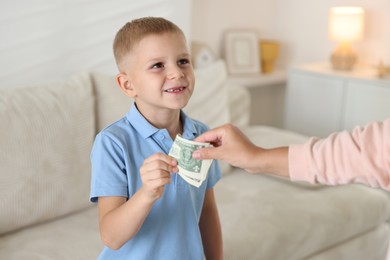 Photo of Mother giving pocket money to her son at home, closeup
