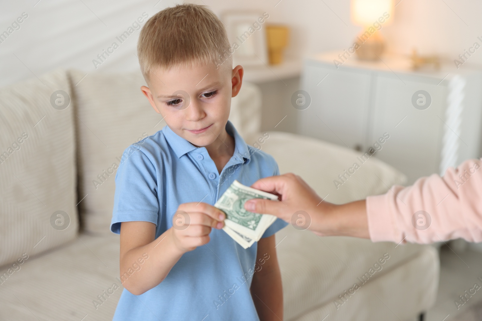 Photo of Mother giving pocket money to her son at home, closeup