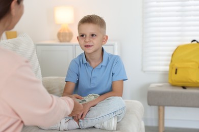 Photo of Mother giving pocket money to her son at home, closeup