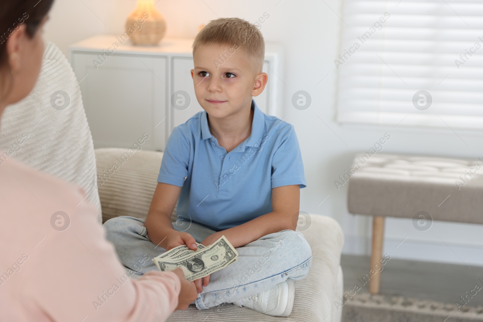 Photo of Mother giving pocket money to her son at home, closeup