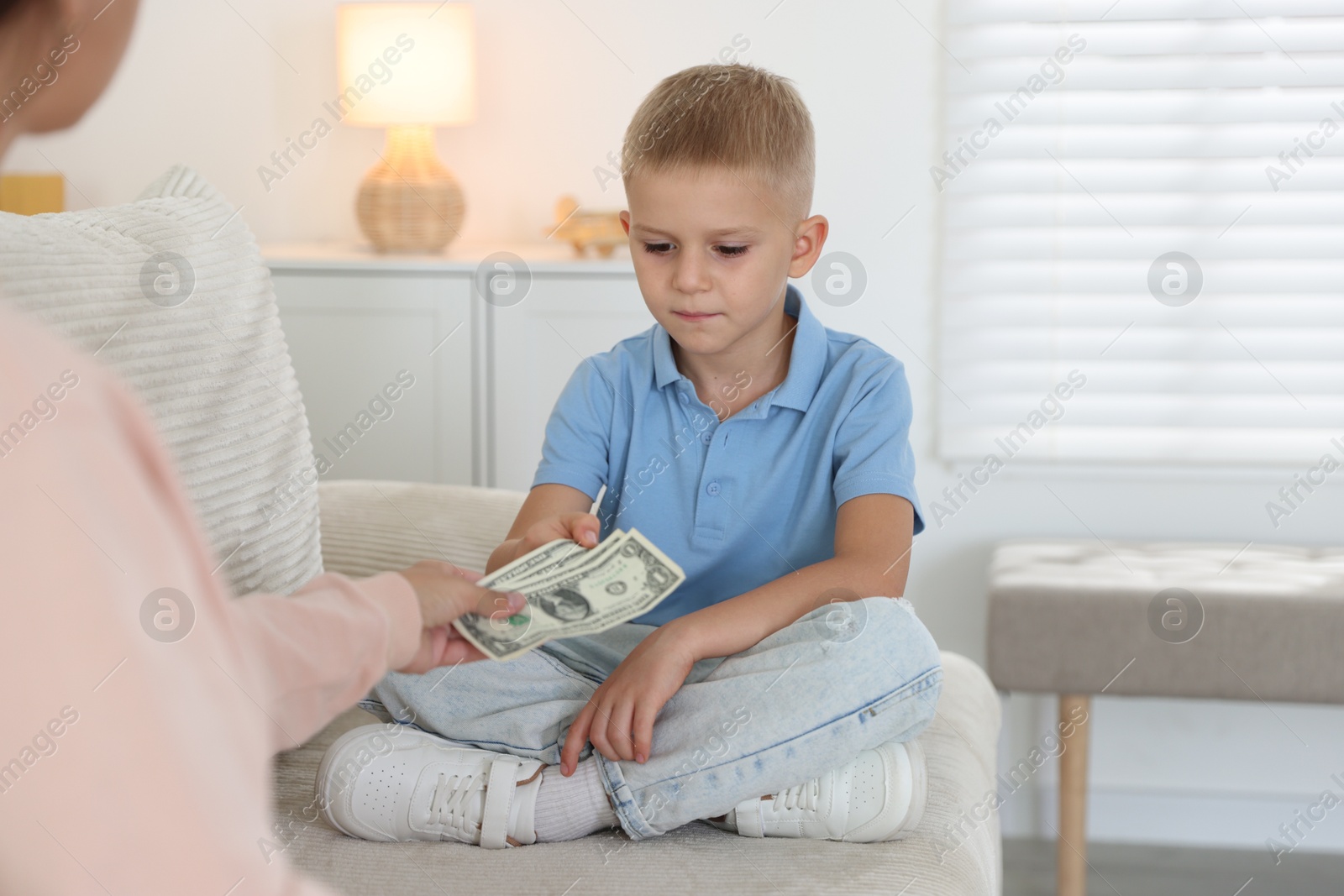 Photo of Mother giving pocket money to her son at home, closeup