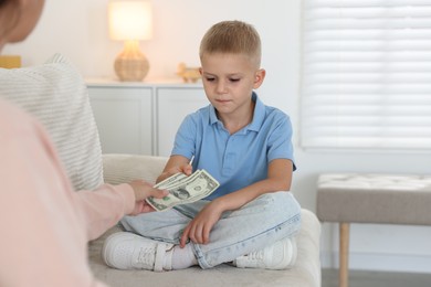 Photo of Mother giving pocket money to her son at home, closeup