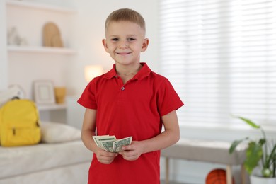 Photo of Little boy holding pocket money at home