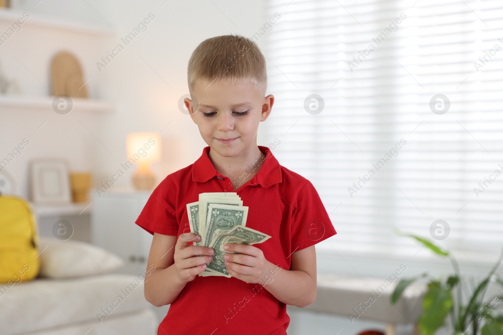 Photo of Little boy holding pocket money at home